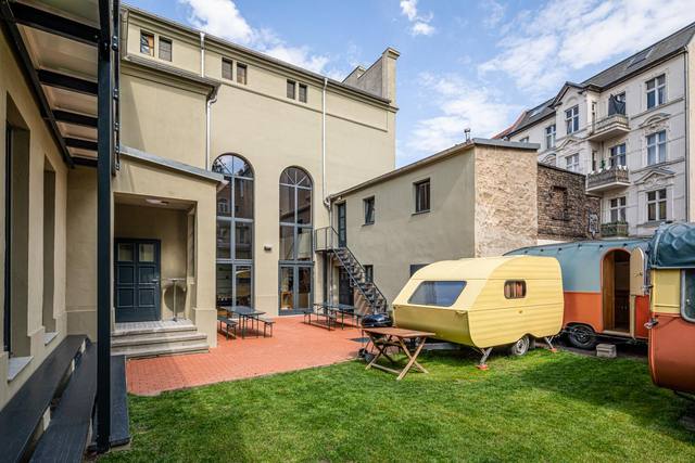 Innenhof mit Rasen und gelbem Wohnwagen