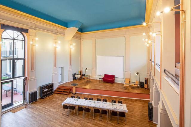 Saal mit langer Tafel vor der Bühne