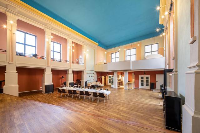 Saal mit langer Tafel, darüber die Empore