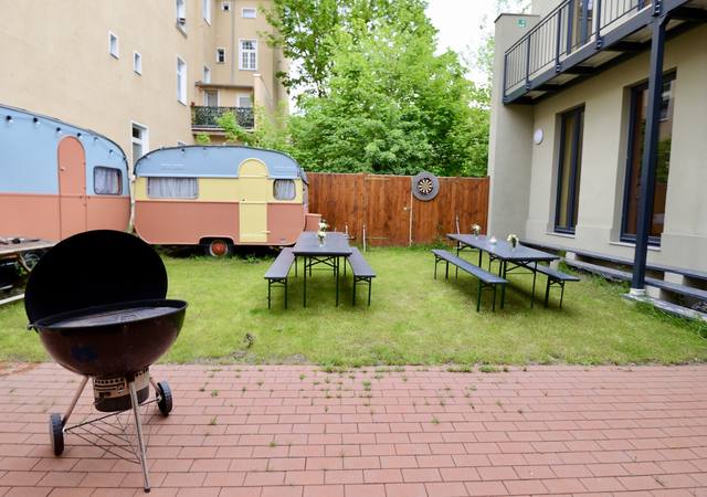 Hof mit Grill, Bierzeltgarnituren und Wohnwagen